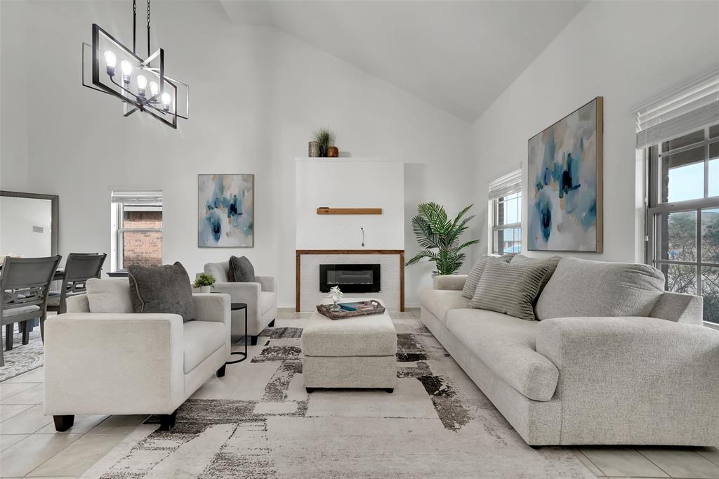 Tiled living room with a notable chandelier, a glass covered fireplace, and high vaulted ceiling