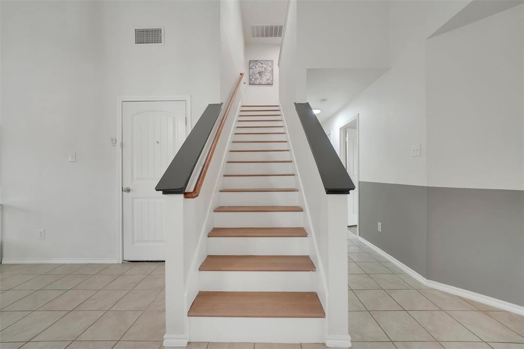 Stairway with tile patterned floors, visible vents, and baseboards