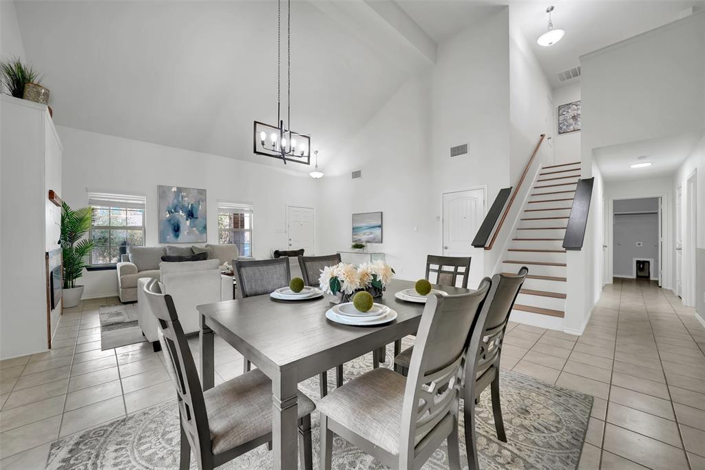 Dining area with light tile patterned floors, stairway, high vaulted ceiling, and visible vents