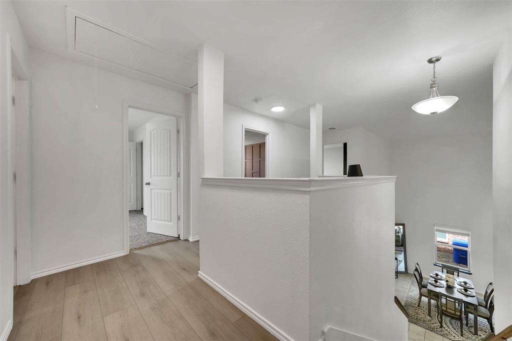 Hall with light wood-style flooring, attic access, and baseboards
