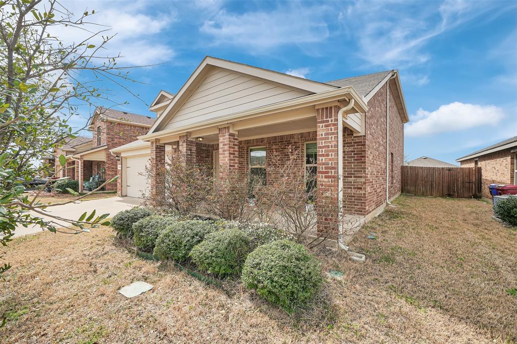 View of front of property with brick siding, fence, a front yard, a garage, and driveway