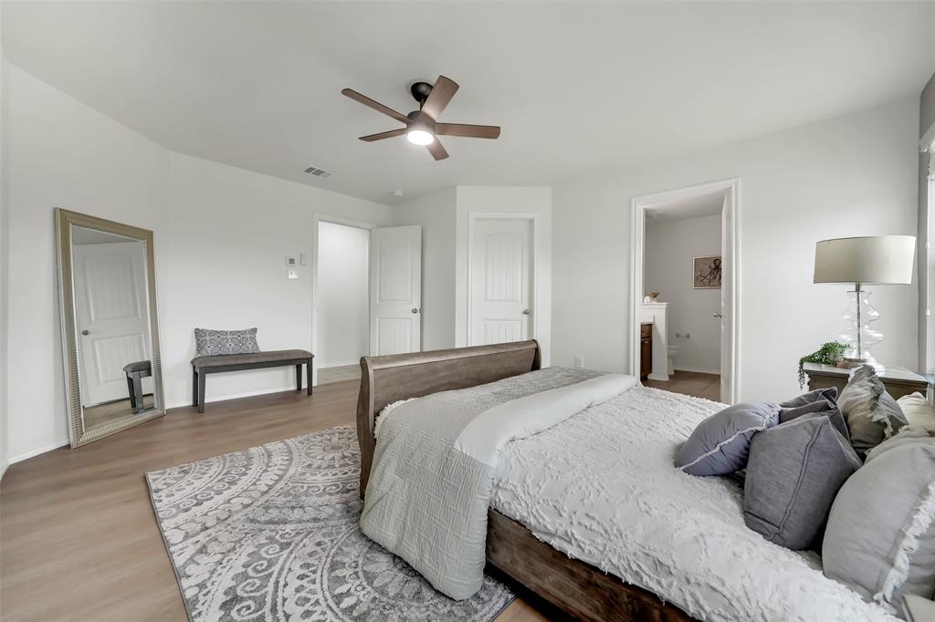 Bedroom with baseboards, visible vents, ensuite bath, ceiling fan, and light wood-type flooring