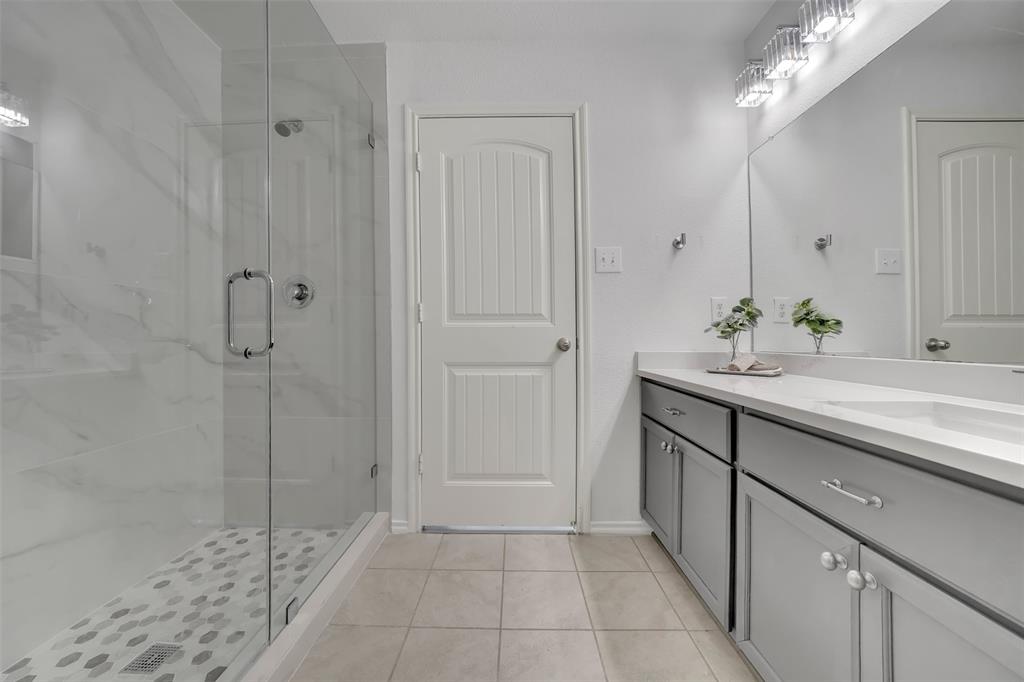 Full bathroom featuring vanity, baseboards, a stall shower, and tile patterned flooring