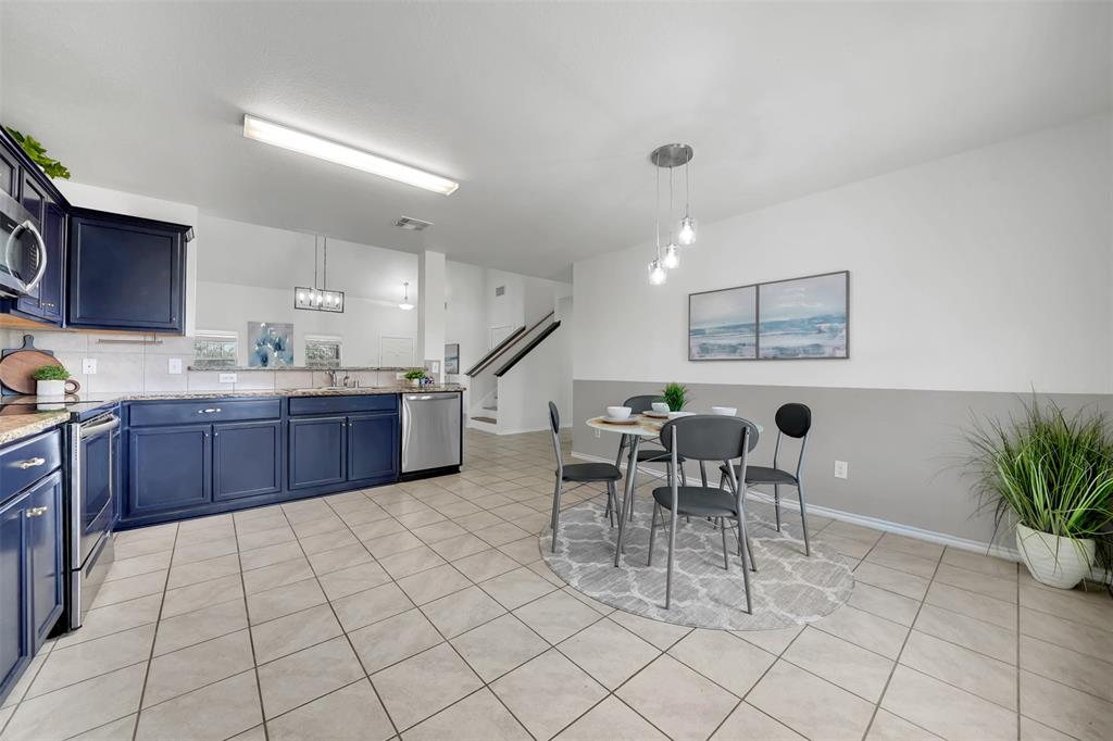 Kitchen featuring light tile patterned floors, blue cabinetry, stainless steel appliances, and a sink