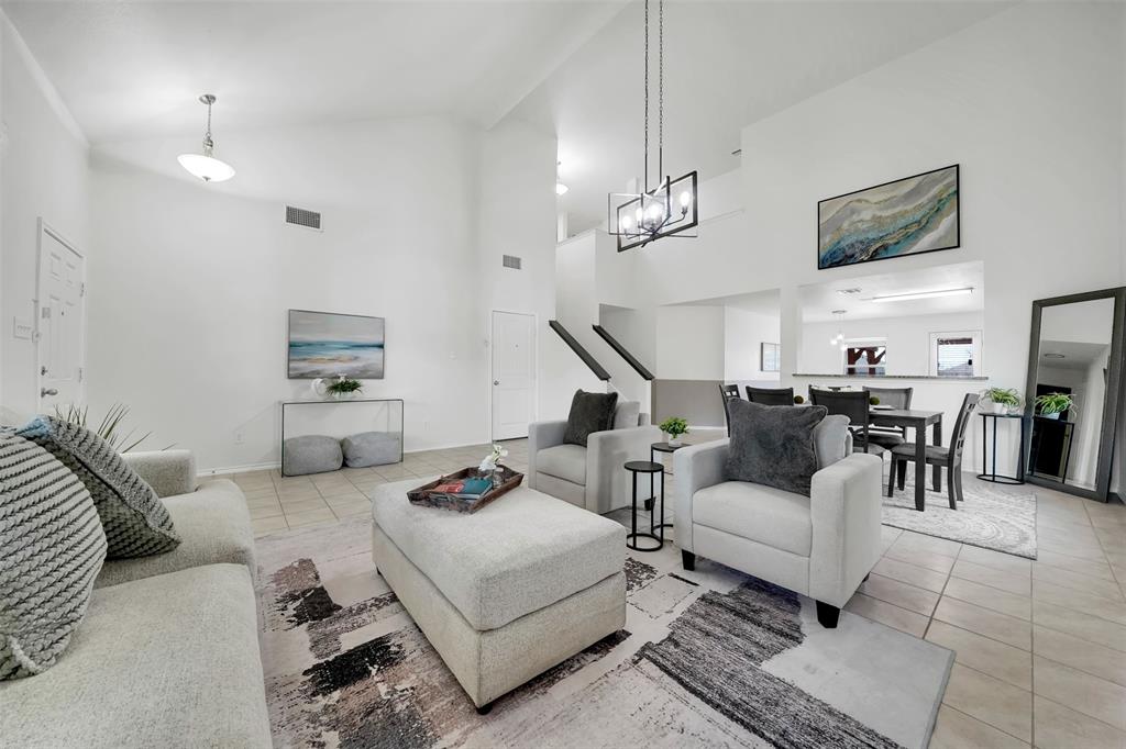 Tiled living area with visible vents, a chandelier, and vaulted ceiling