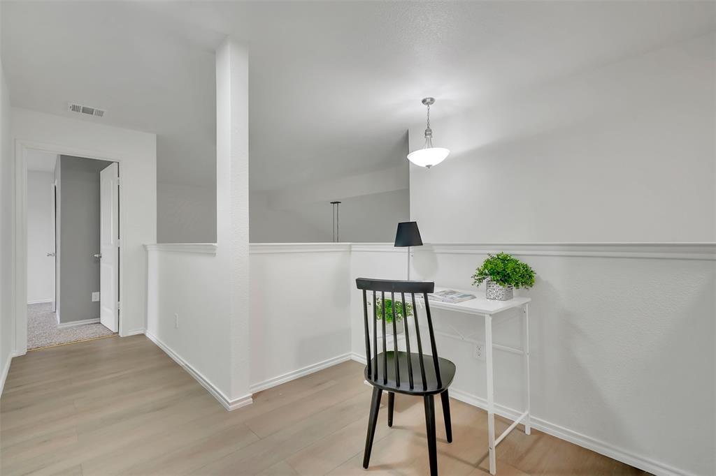 Office area with wood finished floors, visible vents, and baseboards