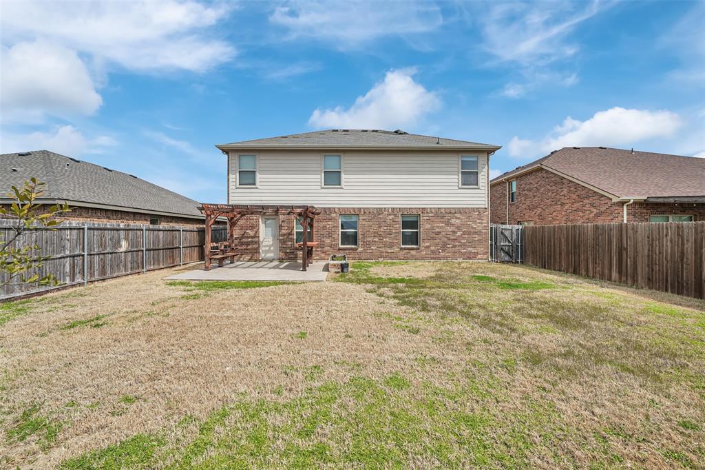 Rear view of property with a yard, a fenced backyard, a pergola, a patio area, and brick siding