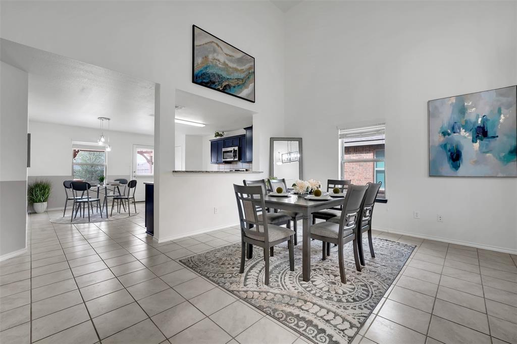 Dining space with light tile patterned floors, baseboards, and a towering ceiling