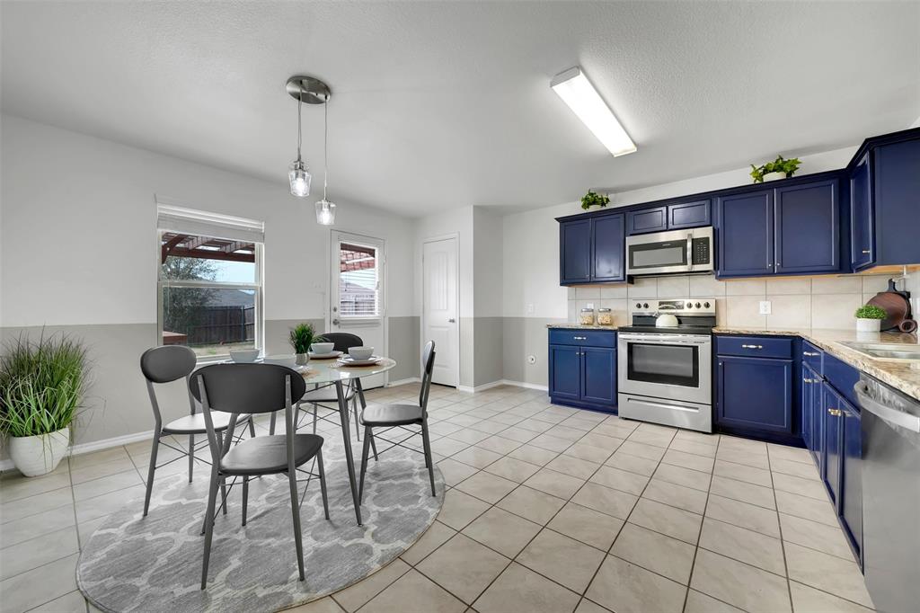 Kitchen featuring blue cabinets, backsplash, stainless steel appliances, light countertops, and light tile patterned floors