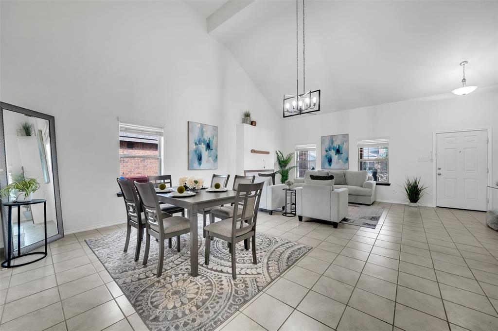 Dining space featuring light tile patterned floors, baseboards, high vaulted ceiling, and a wealth of natural light