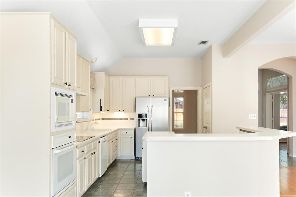 Kitchen featuring light-toned cabinetry, stainless steel appliances, tile flooring, and a peninsula counter