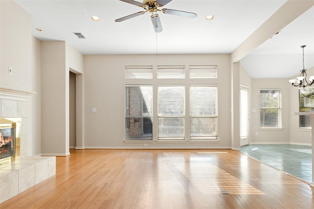 Living area featuring light-toned wood-finish flooring, a tiled fireplace surround, expansive windows with transom glass, recessed lighting, and a ceiling fan