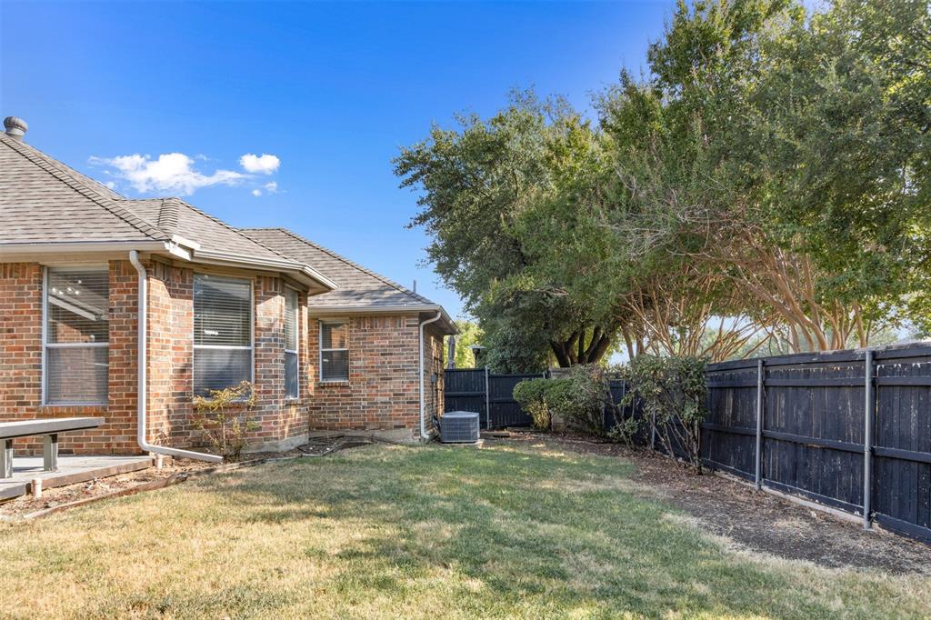 Brick exterior featuring a hip roof, a concrete patio, and a fenced backyard with mature trees