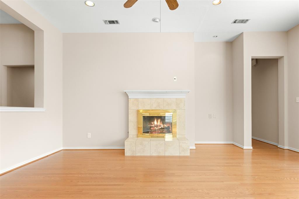 Fireplace with tile surround, wood-finish flooring, ceiling fan, and recessed lighting