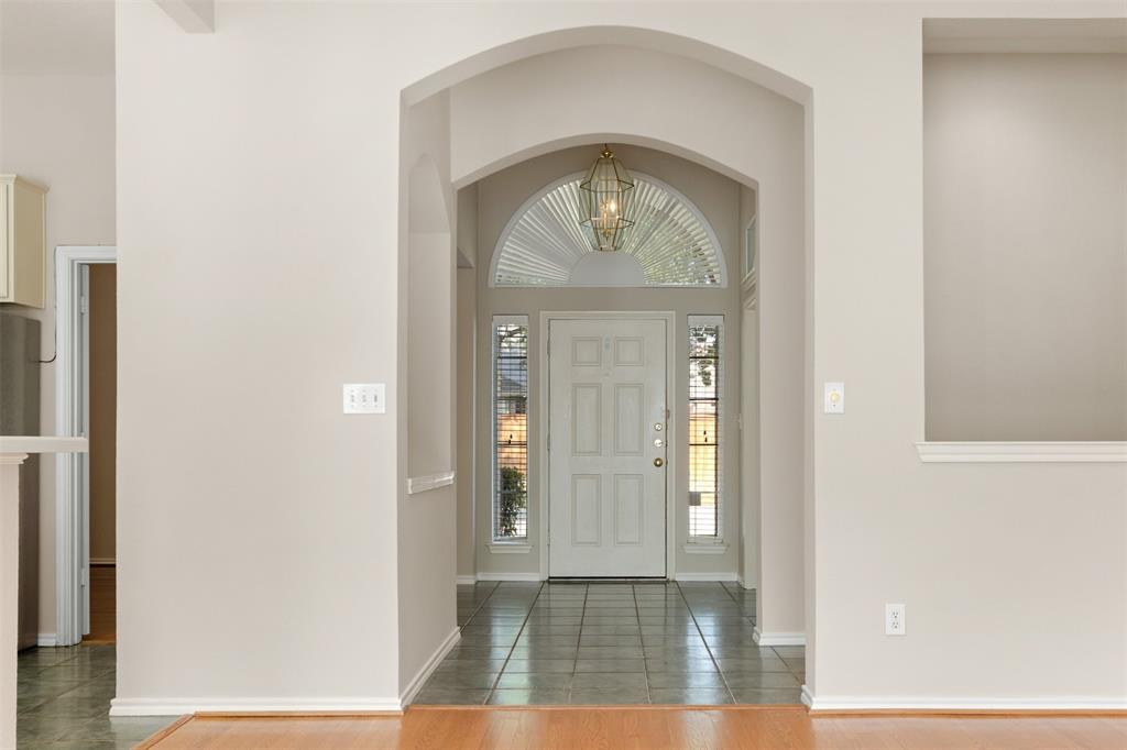 Entryway featuring a decorative arched architectural opening, tile flooring, and a glass-paneled front door with a semi-circular transom window