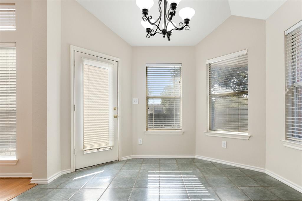 Vaulted ceiling featuring a wrought iron chandelier, ceramic tile flooring, and multiple windows with integrated blinds