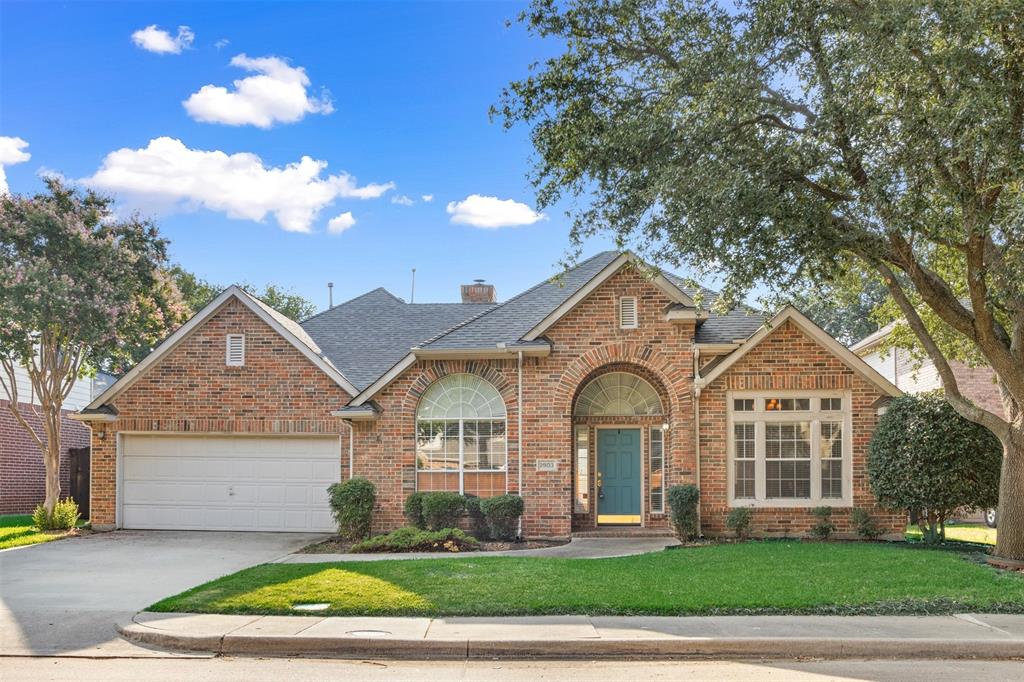 Brick exterior featuring an arched entryway, gabled rooflines, multi-pane windows, and a two-car garage