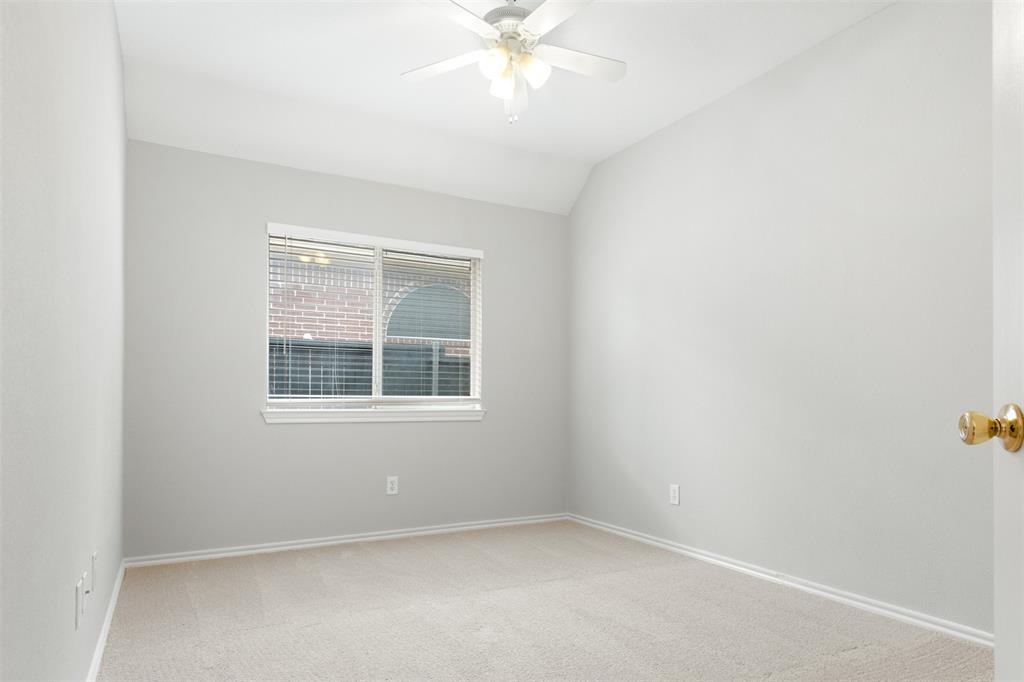 Neutral-toned room featuring a vaulted ceiling, neutral wall-to-wall carpeting, a multi-light ceiling fan, and a single-pane window