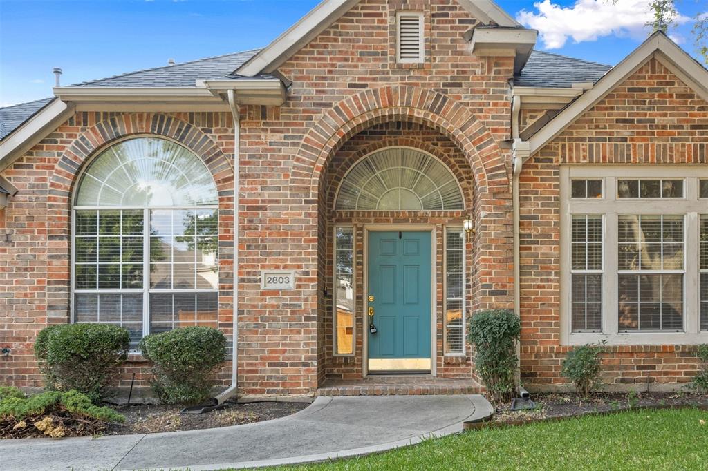 Exterior facade featuring multi-tonal brick construction, an arched entryway, decorative fanlight windows, and a panelled front door
