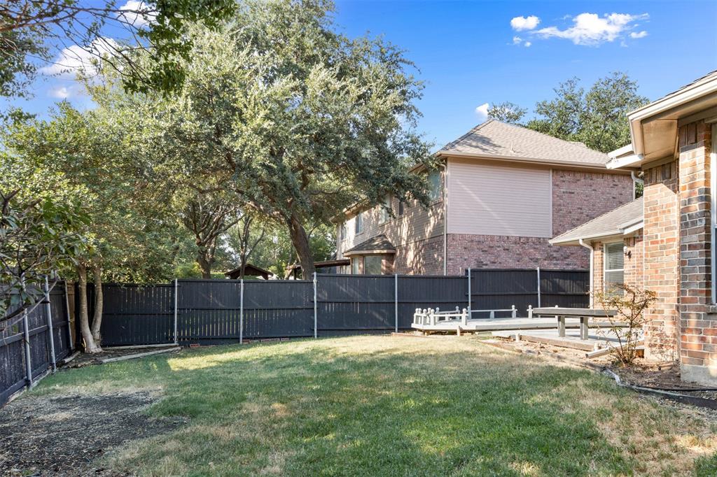 Backyard featuring a grass lawn, mature trees, a tiered wood deck, and a full-perimeter privacy fence