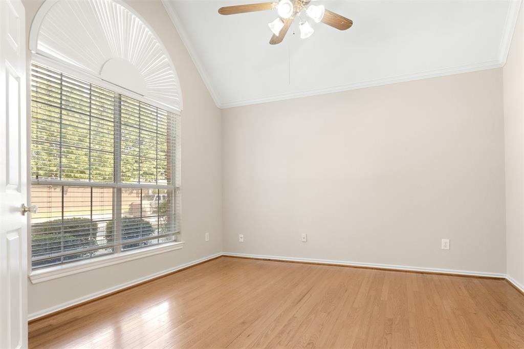 Vaulted ceiling, wood-finish flooring, and an arched transom window featuring horizontal blinds and an attached ceiling fan