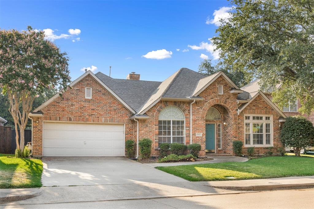 Traditional brick exterior featuring an arched entryway, multiple gabled rooflines, divided-lite windows with arched upper accents, and an attached two-car garage