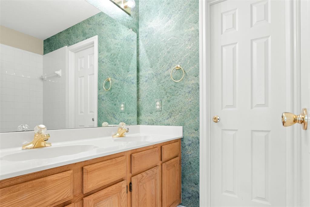 Dual-sink vanity with white countertop, large frameless mirror, and metallic gold-finish fixtures