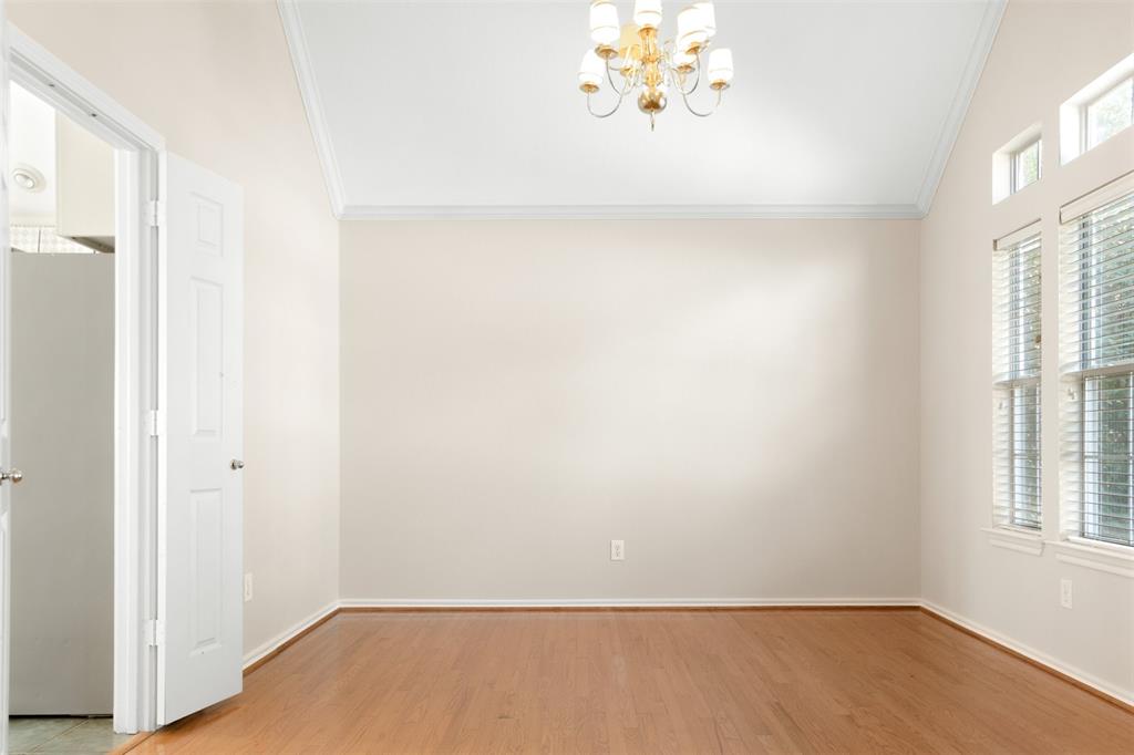 Vaulted ceiling with crown molding, wood-finish flooring, multi-pane windows with horizontal blinds, and a multi-arm metallic chandelier