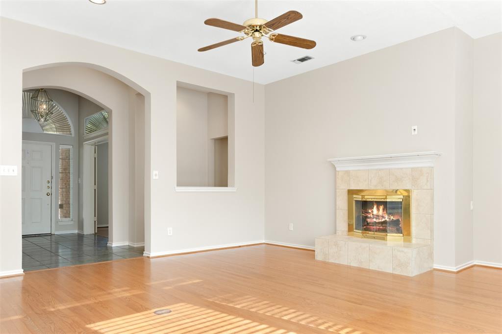 Living area featuring wood-finish flooring, a recessed wall niche, a fireplace with a neutral-toned tile surround, and an arched entryway