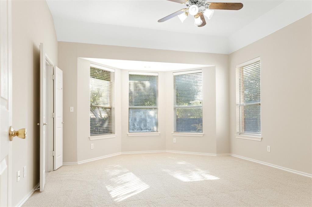 Room featuring neutral wall-to-wall carpeting, vaulted ceiling with a central multi-light ceiling fan, and a three-paneled bay window