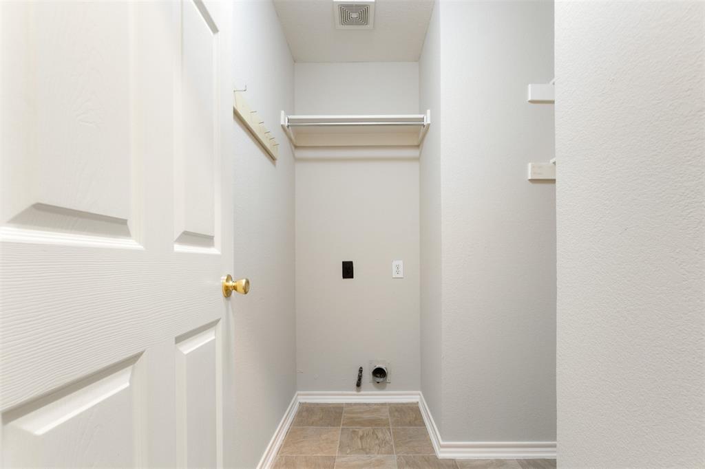 Utility space featuring tile flooring, built-in shelving, wall-mounted racks, and dedicated hookups