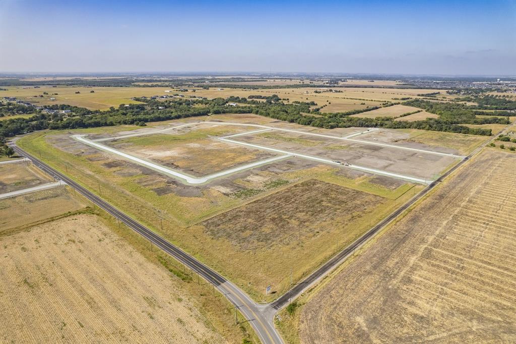 Expansive acreage featuring cleared land, established asphalt road access, and perimeter tree lines