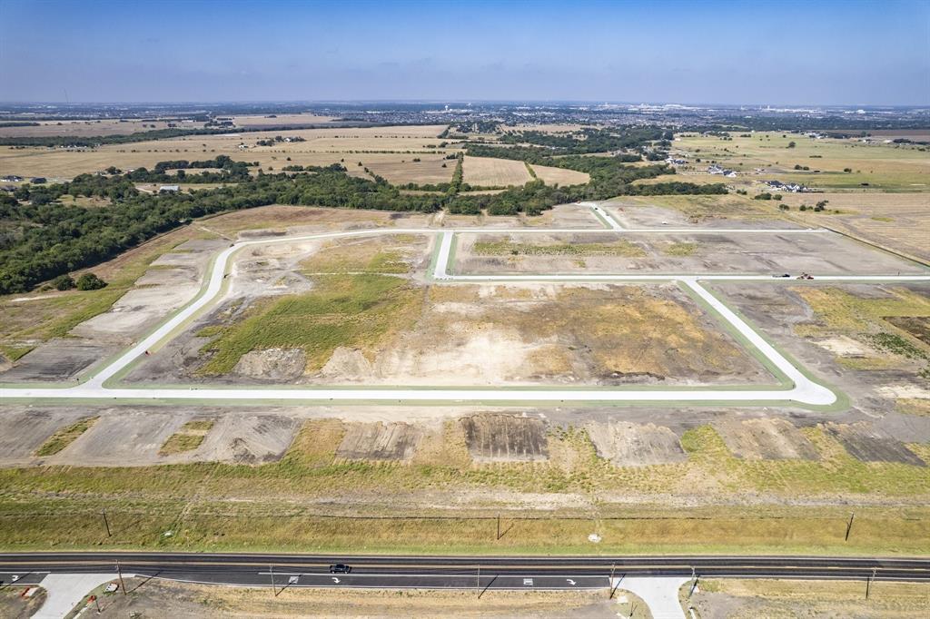 Expansive plot of undeveloped land featuring paved street infrastructure, concrete curbing, and surrounding open terrain Expansive plot of undeveloped land featuring paved street infrastructure, concrete curbing, and surrounding open terrain