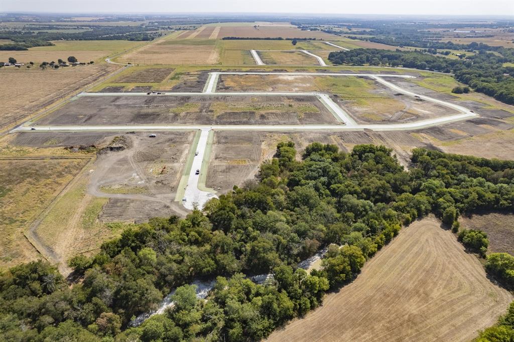 Expansive land parcel featuring established concrete roadway infrastructure, cleared building sites, and dense perimeter tree coverage Expansive land parcel featuring established concrete roadway infrastructure, cleared building sites, and dense perimeter tree coverage