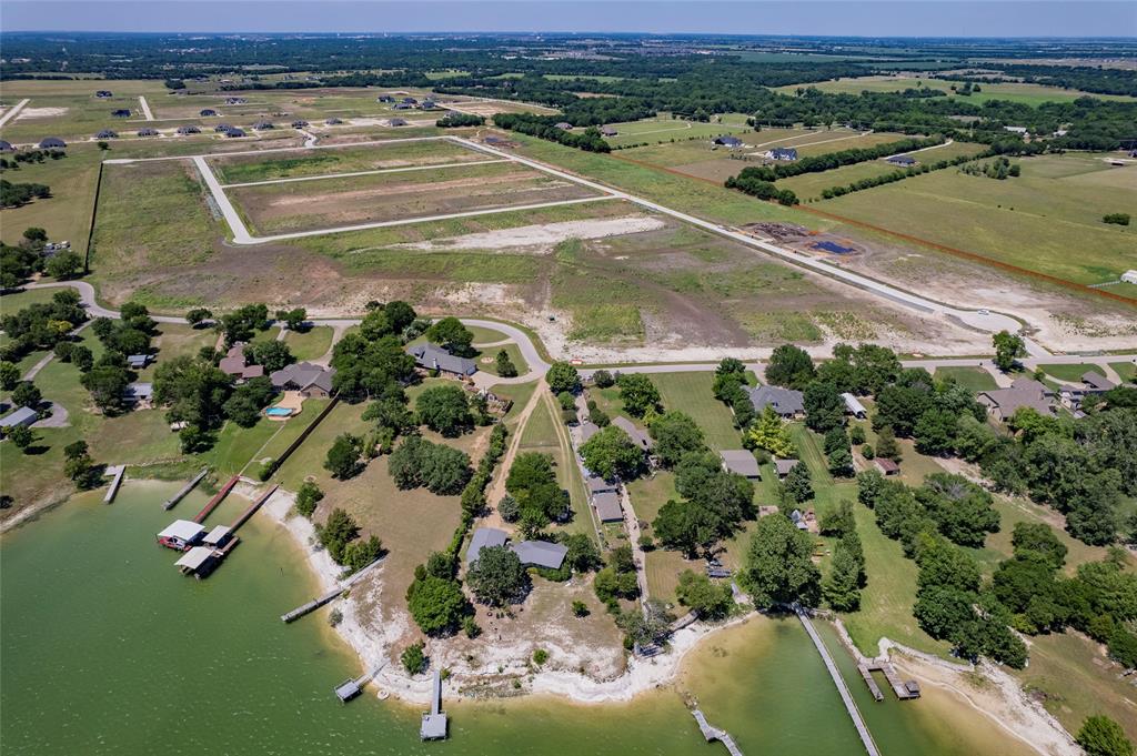 Aerial perspective of waterfront acreage featuring a natural shoreline, multiple private boat docks, and established mature tree canopy