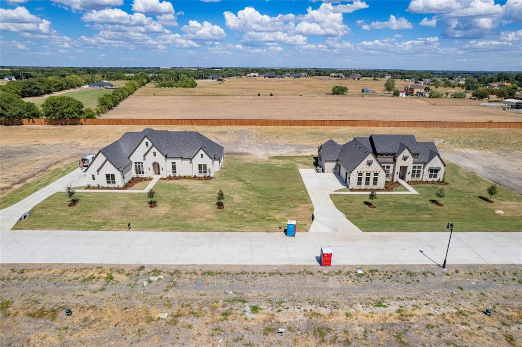 Two modern stone-veneer residences featuring steep-pitched rooflines, expansive manicured lots, and concrete driveways situated on a large rural parcel