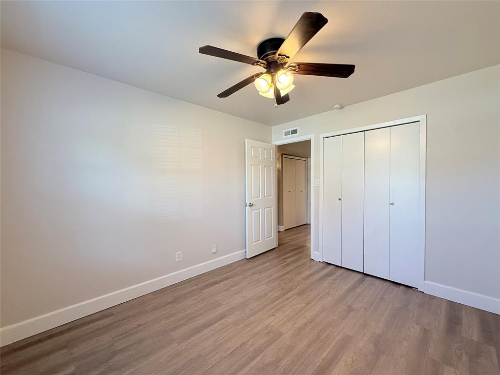 Neutral wall tones, wood-finish flooring, ceiling fan with integrated lighting, and multi-panel bi-fold closet doors