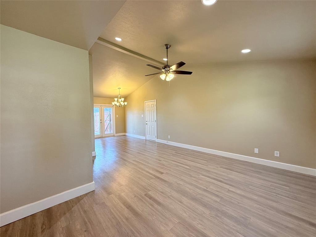 Interior space featuring vaulted ceilings, wood-finish flooring, recessed lighting, a ceiling fan with integrated lighting, and a multi-pane glass door