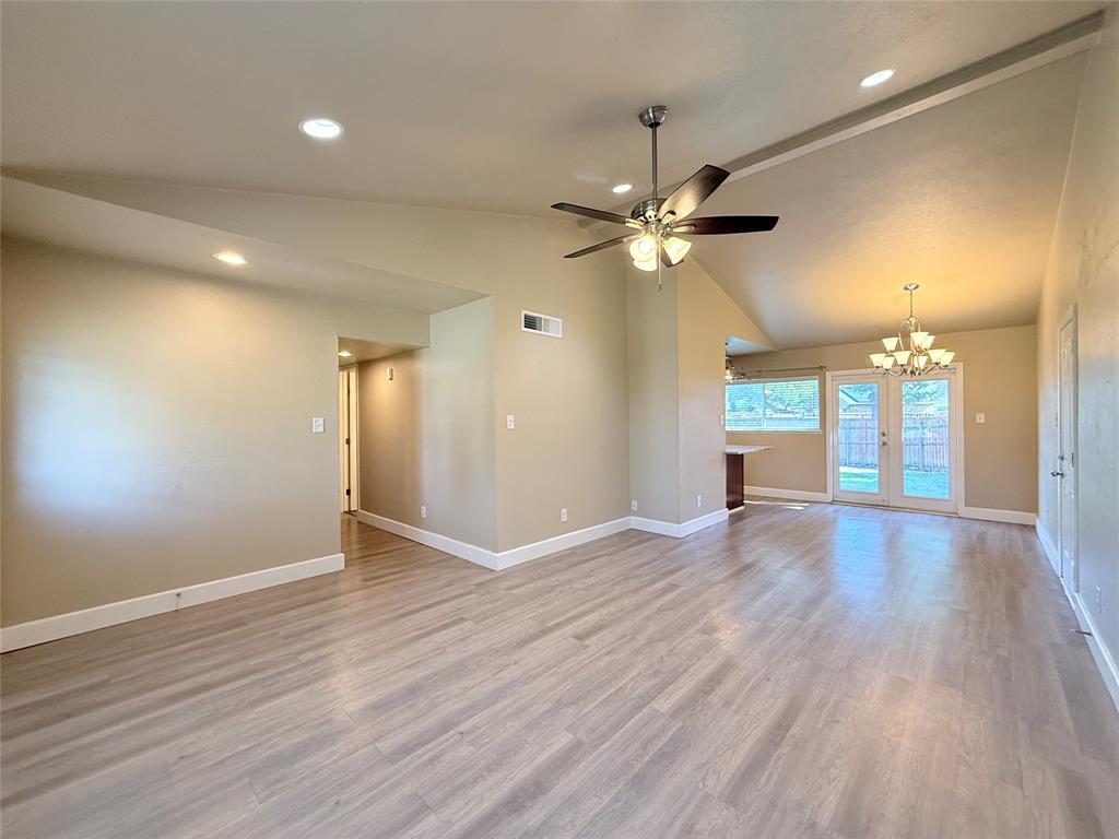 Vaulted ceilings, wood-finish flooring, recessed lighting, ceiling fan with light kit, and double glass-paned doors
