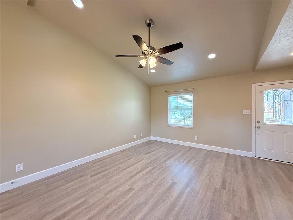 Vaulted ceiling featuring recessed lighting and a brushed-nickel ceiling fan, light-toned wood-finish flooring, and an exterior door with decorative glass paneling