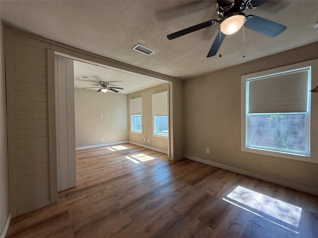 Wood-finish flooring, paneled wall detailing, and dual ceiling fans with integrated lighting fixtures