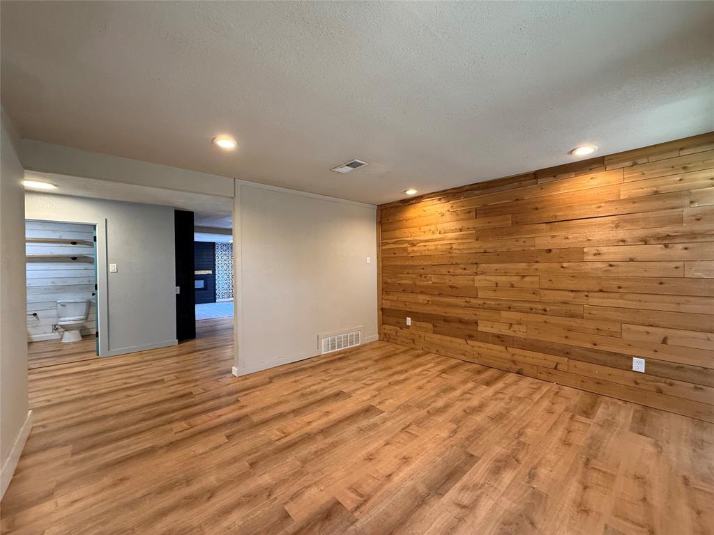 Interior space featuring wood-finish flooring, a horizontal wood-plank accent wall, recessed lighting, and wall-mounted shelving