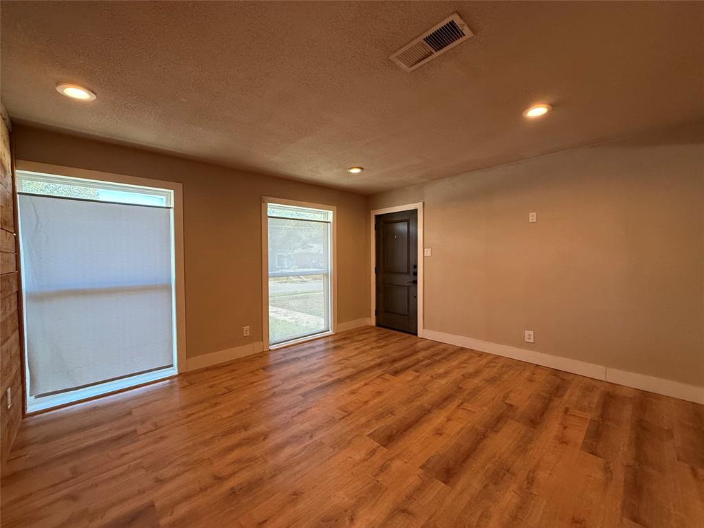 Interior space featuring wood-finish flooring, two large windows, recessed lighting, and a dark-toned solid door
