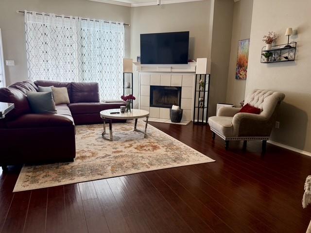 Living area featuring dark wood-finish flooring, a fireplace with a light-toned tile surround, and a classic white mantel