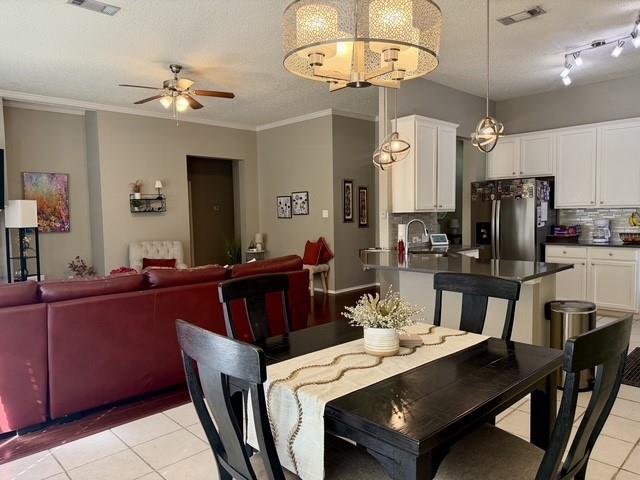 Open-concept interior featuring white cabinetry, a kitchen island with stone-surface countertop, drum-style ceiling light fixtures, and tiled flooring