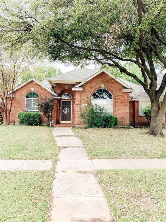 Traditional brick exterior featuring arched windows, a covered recessed entryway, and mature shade trees
