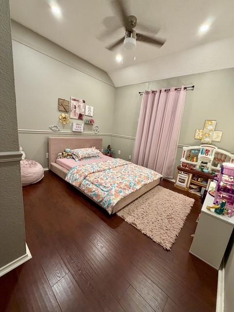 Room featuring wood-finish flooring, vaulted ceilings, chair rail molding, and a central ceiling fan with integrated lighting