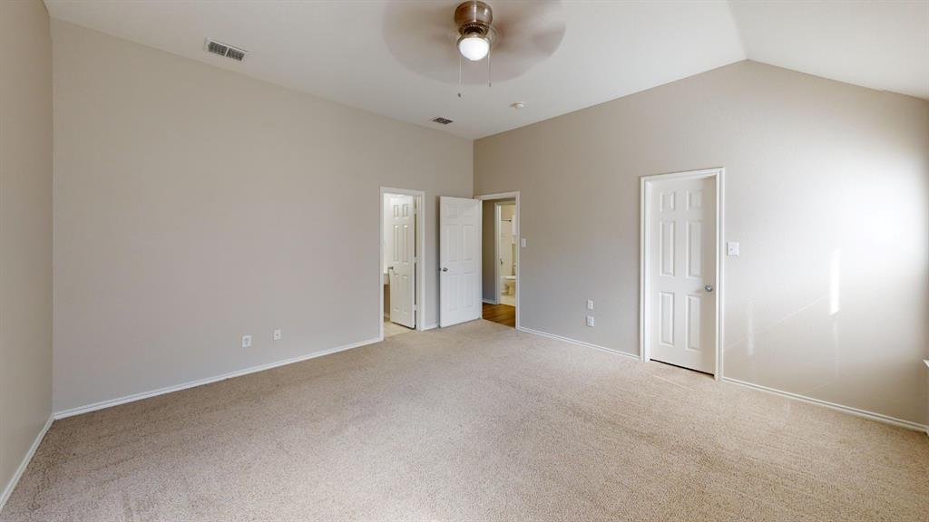 Vaulted ceilings, neutral wall tones, carpeted flooring, and a ceiling fan with integrated lighting