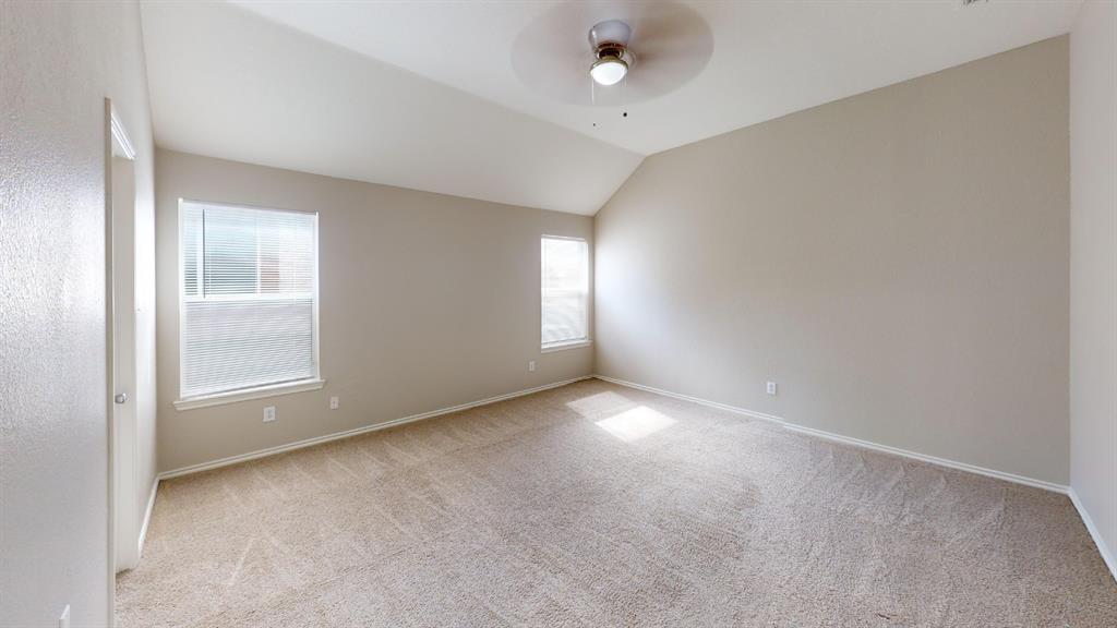 Vaulted ceiling, neutral wall tones, wall-to-wall carpeting, two dual-pane windows, and a ceiling fan with integrated light fixture