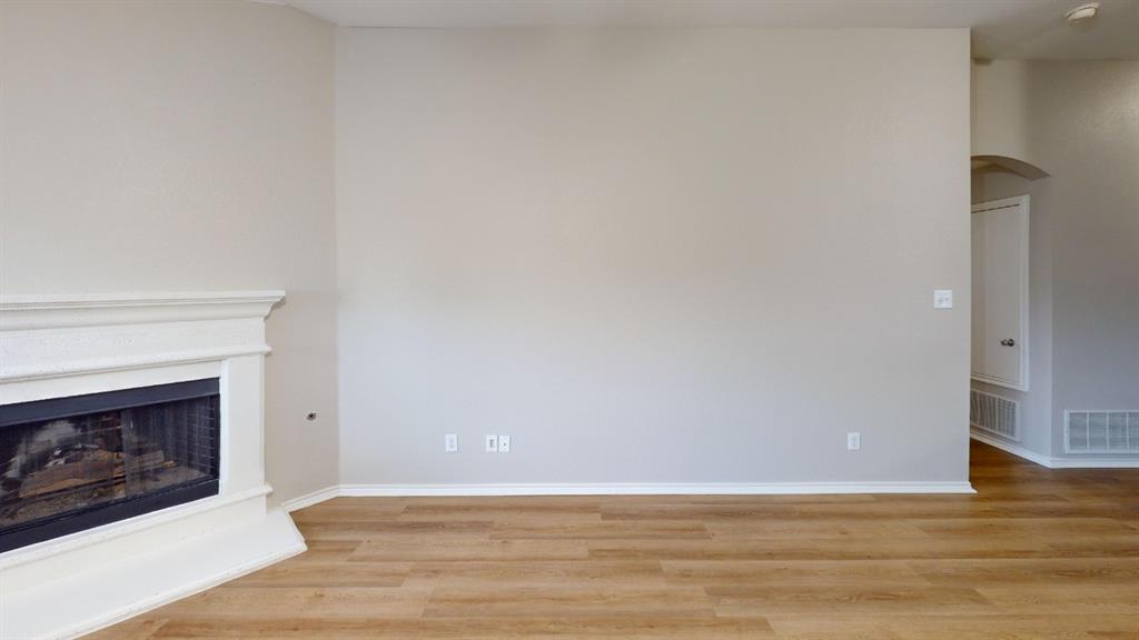 Fireplace with a classic white mantel, neutral wall tones, and wood-finish flooring